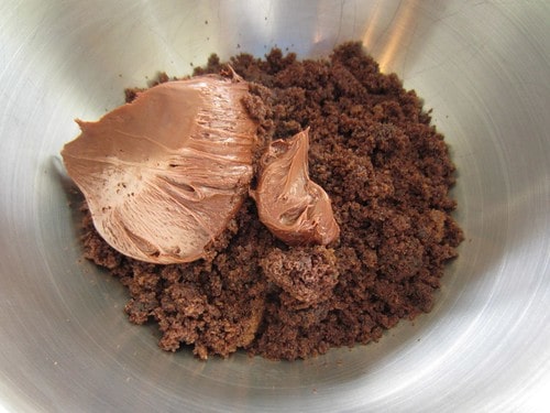 Chocolate cake crumbles and chocolate frosting in a bowl