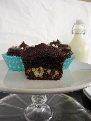 A half of a Chocolate Cream Cheese Cupcake on a plate with two other cupcakes
