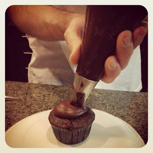 Chocolate frosting being piped onto a Chocolate Cream Cheese cupcake