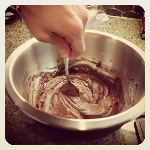 Chocolate frosting being stirred with a spoon