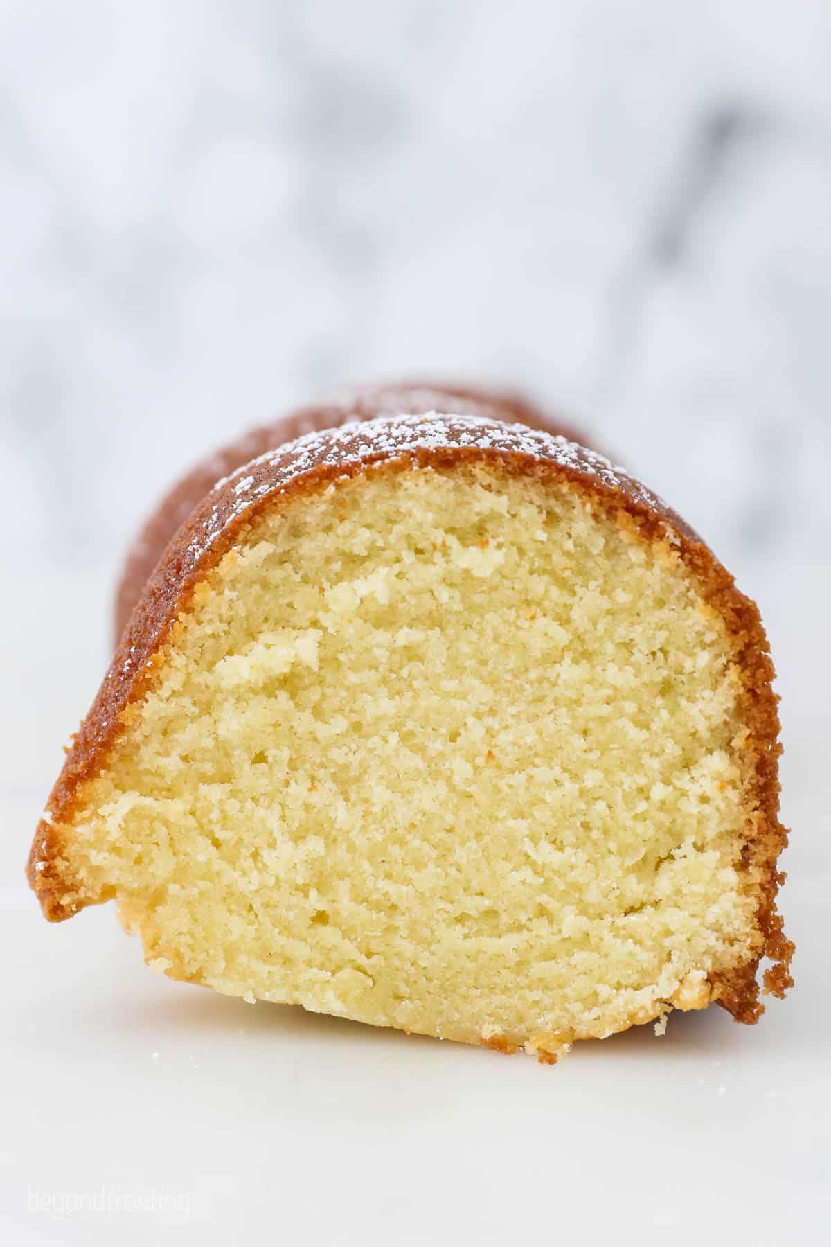 A slice of pound cake topped with a dusting of powdered sugar shown from the side