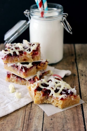 Lemon Raspberry Shortbread Magic bars stacked in front of a glass of milk
