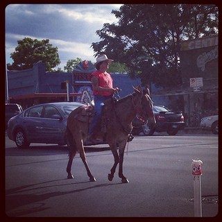 A woman riding a horse in a parking lot