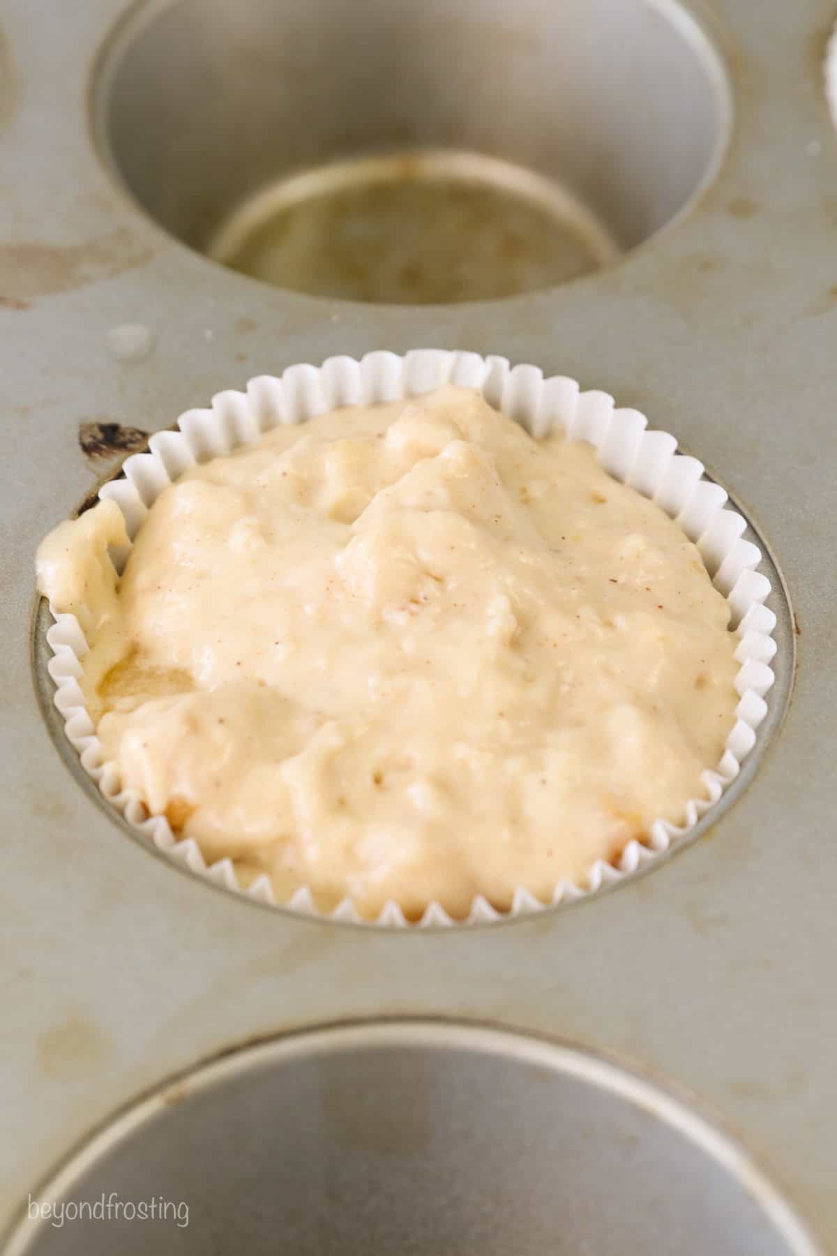 Close up view of peach macadamia nut muffin batter in a muffin tin.