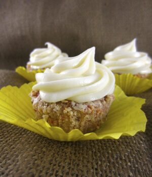 Three Gluten-Free Carrot Cake Cupcakes topped with a vanilla cream cheese frosting.