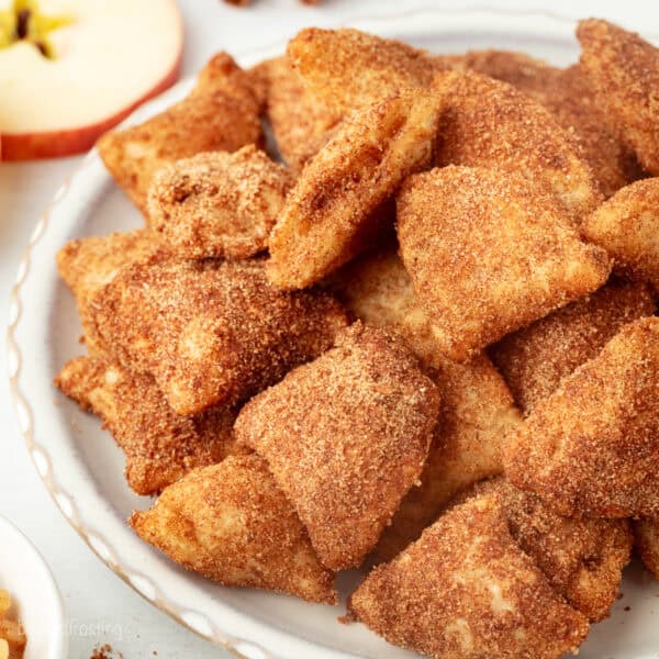 Golden-fried apple pie bites coated with cinnamon sugar on a plate.