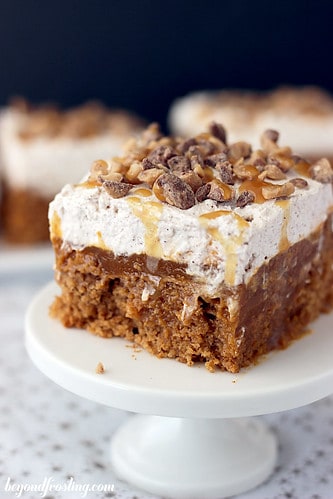 A slice of frosted double pumpkin poke cake on a mini cake stand