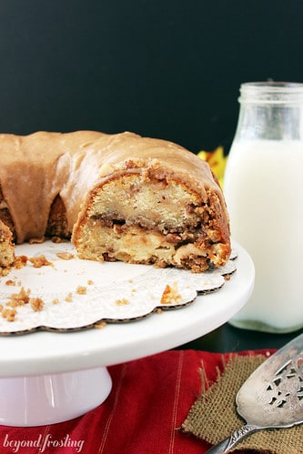 Apple Pie Coffee Cake on a white cake stand with several slices removed