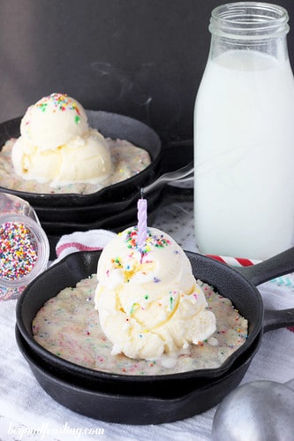 Skillet cookie with a scoop of vanilla ice cream and a candle