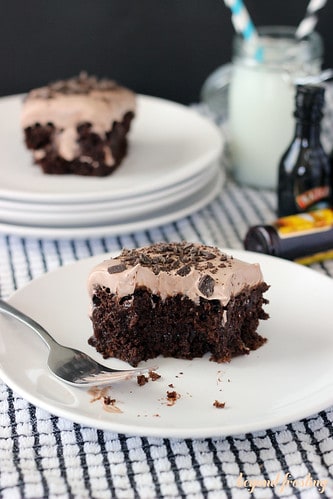 A serving of mudslide poke cake on a plate with a bite removed