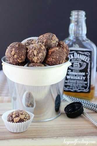 Whiskey Chocolate Toffee Truffles in a tin in front of a bottle of Jack Daniel's Whiskey
