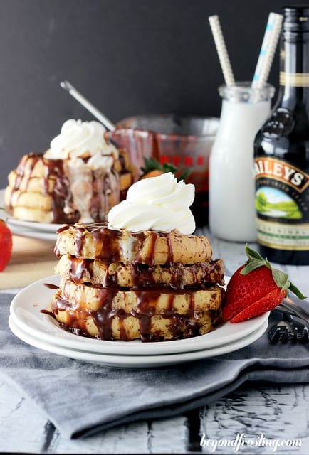 Side view of a stack of Bailey's French Toast on a plate topped with whipped cream