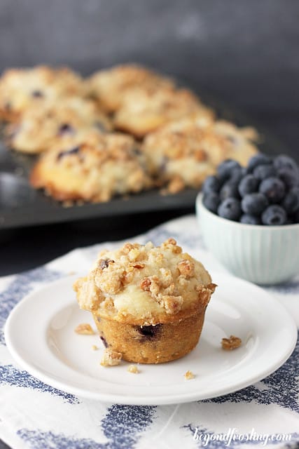 A Coconut Blueberry Muffin on a plate next to a bowl of blueberries