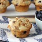 A close up of a Coconut Blueberry Muffin sitting next to a bowl of fresh blueberries