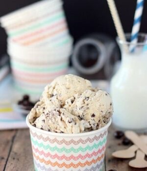 A bowl full of Espresso Chip Cookie Dough Ice Cream with cups and a glass of milk.