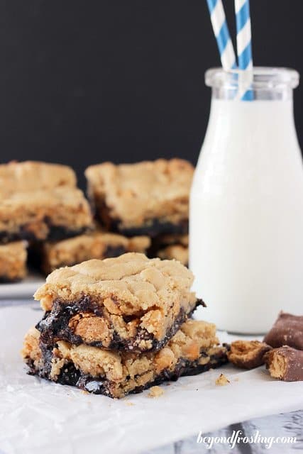 Butterfinger Brookie bars stacked next to a glass of milk