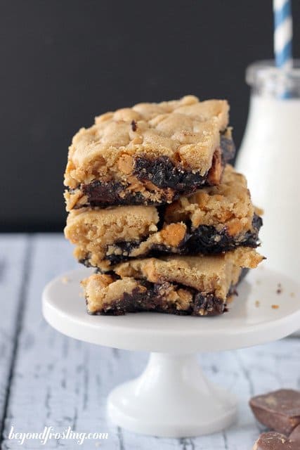 Three Butterfinger Brookie bars stacked on a mini white cake stand