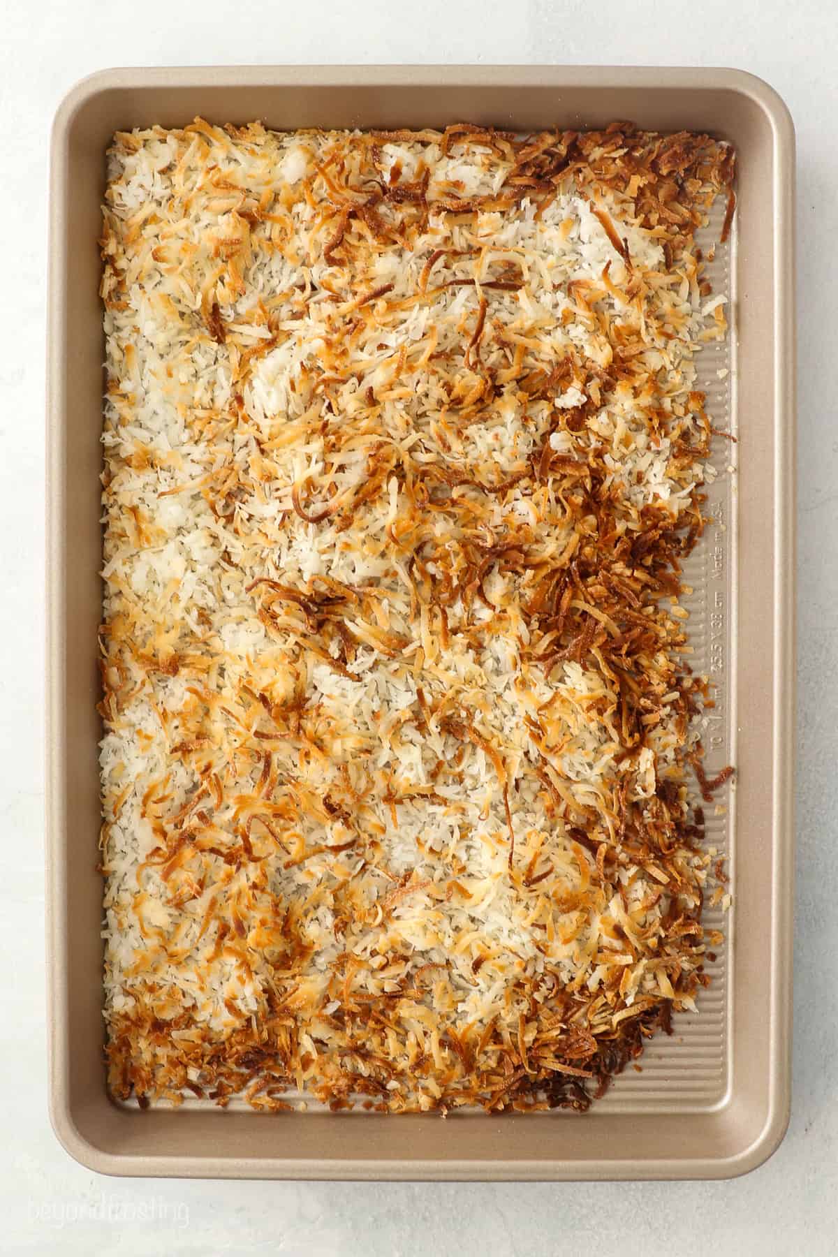 Overhead view of toasted coconut on a sheet pan.