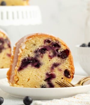 A slice of lemon blueberry bundt cake on a plate next to a fork.