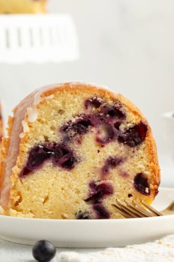 A slice of lemon blueberry bundt cake on a plate next to a fork.