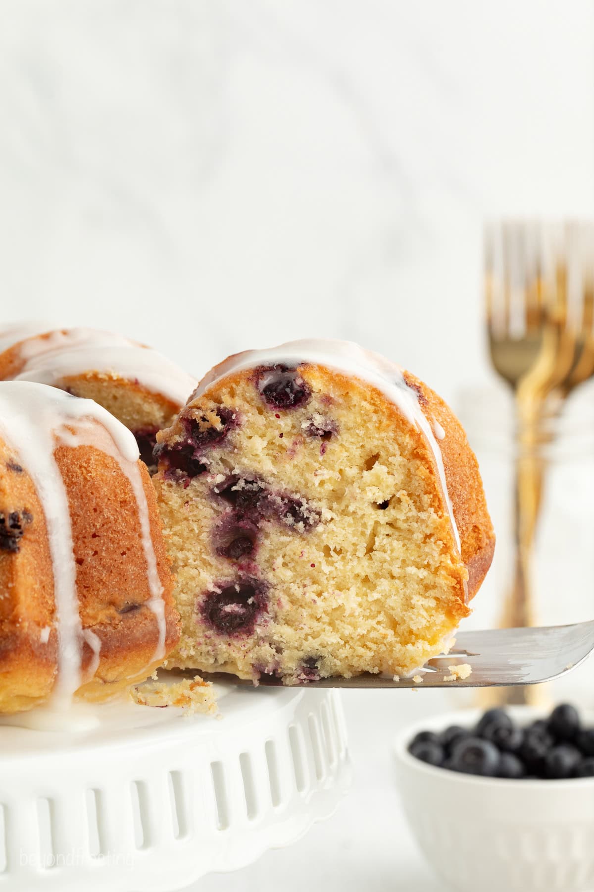Side view of a lemon blueberry bundt cake with a large slice missing.