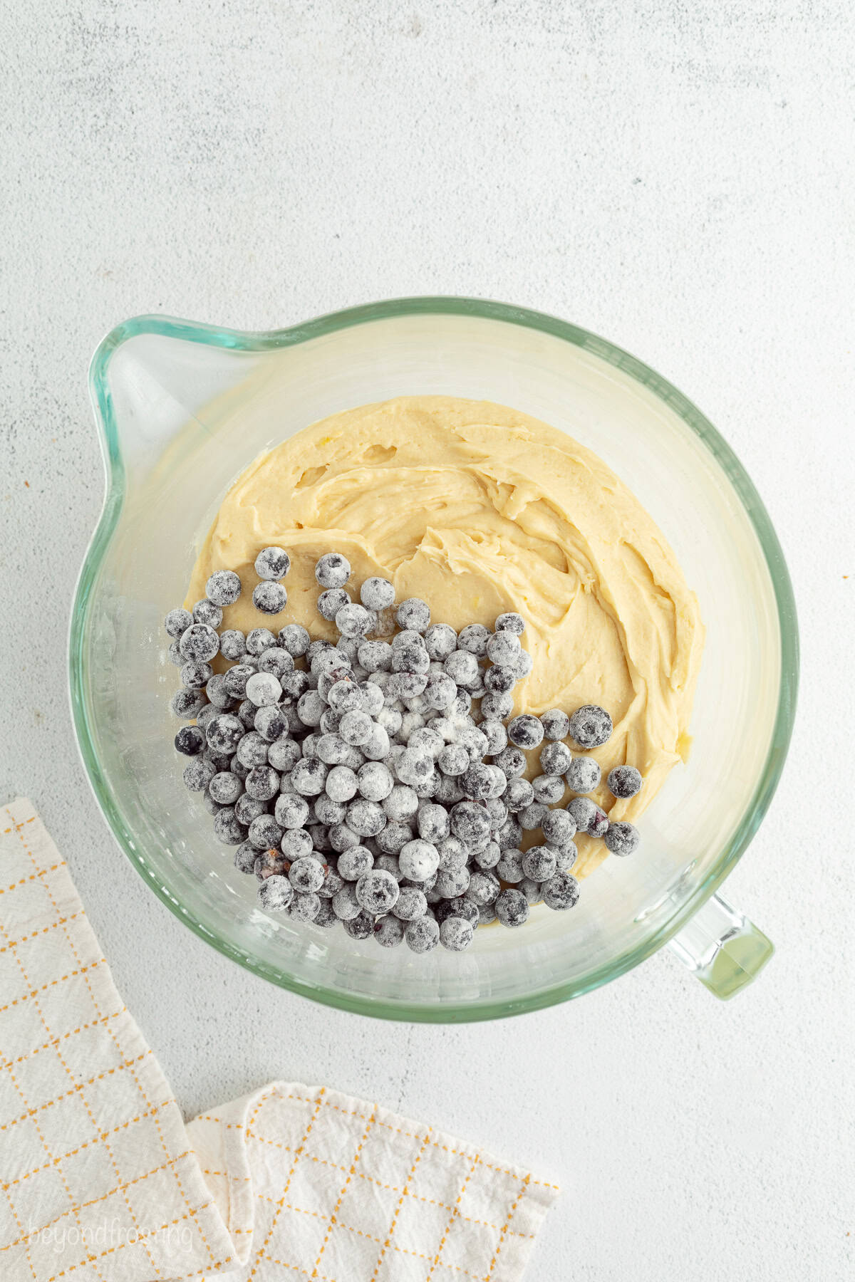 Blueberries added to a bowl of bundt cake batter.