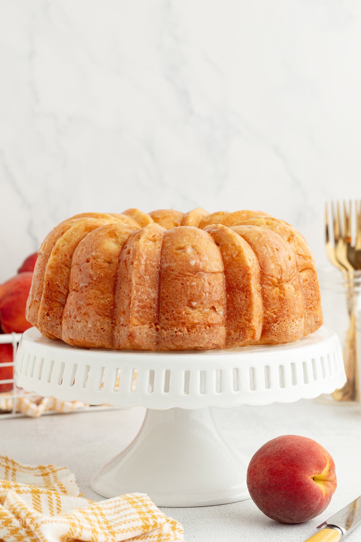A bourbon peach pound cake on a white cake stand.