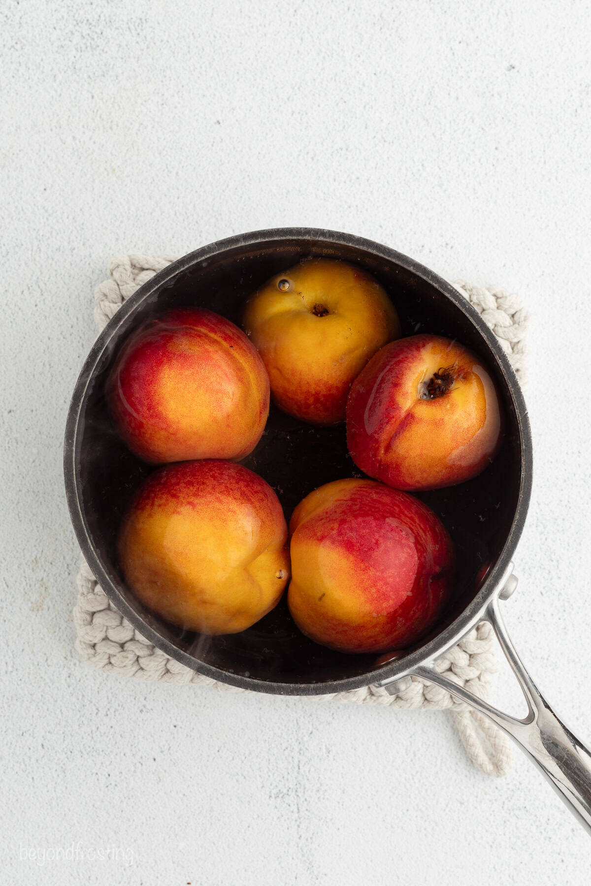 Whole peaches boiling in a pot of water.
