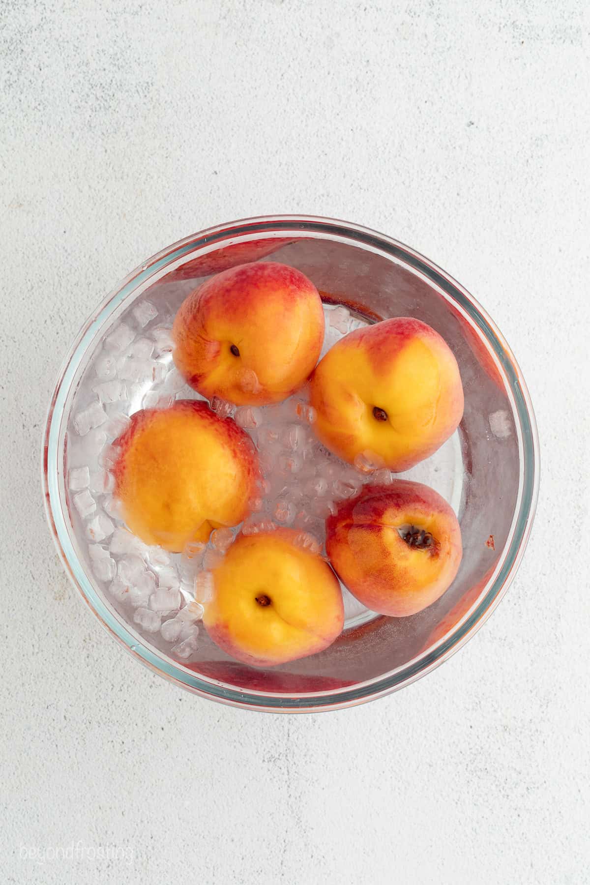 Blanched peaches in a bowl with an ice bath.