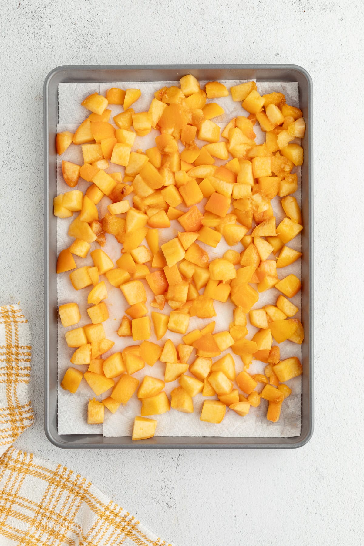 Overhead view of baked peaches on a lined sheet pan.