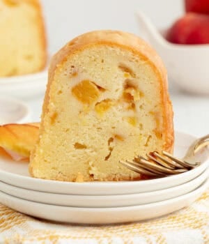 A slice of bourbon peach pound cake next to a fork on a plate.
