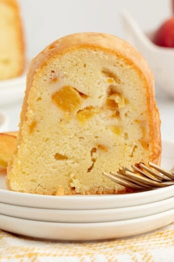 A slice of bourbon peach pound cake next to a fork on a plate.