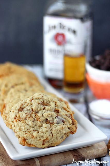 Bourbon Salted Caramel Oatmeal Cookies lined up on a tray in front of a bottle of Jim Beam