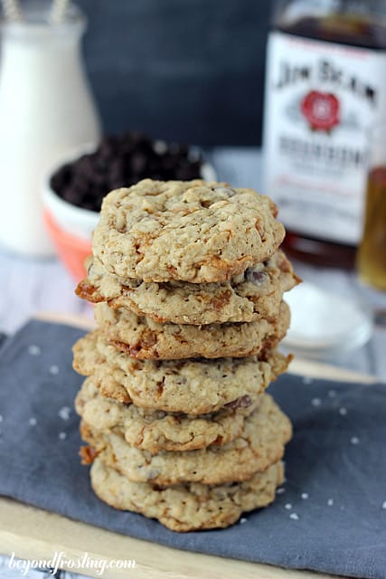 Bourbon Salted Caramel Oatmeal Cookies stacked in front of a bottle of Jim Beam