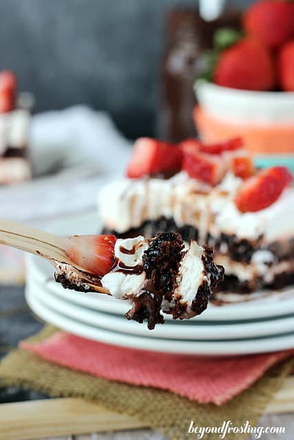 A serving of Brownie Brittle Strawberry Lasagna on a plate with a bite on a fork