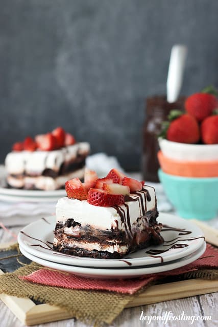 A square of Brownie Brittle Strawberry Lasagna on a plate drizzled with chocolate