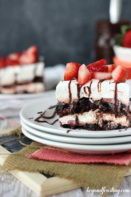 Side view of a serving of Brownie Brittle Strawberry Lasagna on a plate with chocolate drizzle