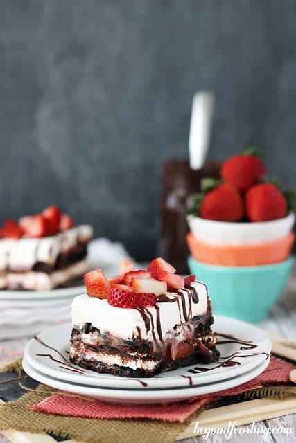 A serving of Brownie Brittle Strawberry Lasagna on a plate with chocolate drizzle