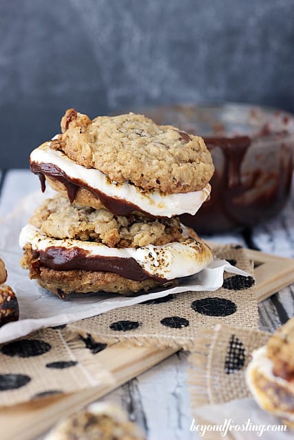 A stack of Bourbon Bacon Smores cookies on burlap in front of a bowl of melted choclate