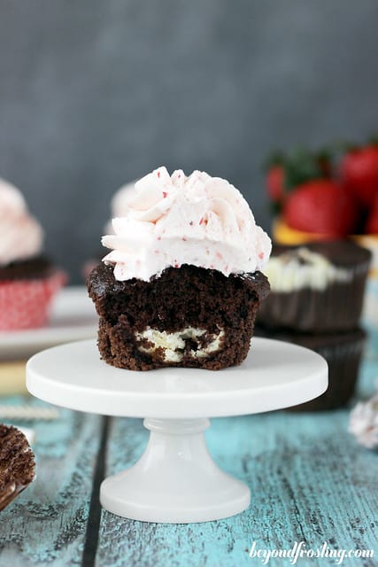 Chocolate Strawberry Cheesecake Cupcake on a cake stand with a bite removed