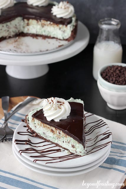 Overhead view of a slice of Brownie Brittle Grasshopper Pie on a plate with chocolate drizzle and a swirl of whipped cream