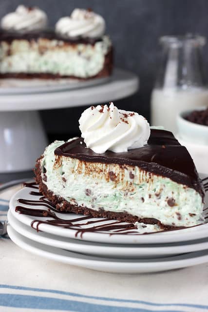 A slice of Brownie Brittle Grasshopper Pie on a plate with a swirl of whipped cream on top