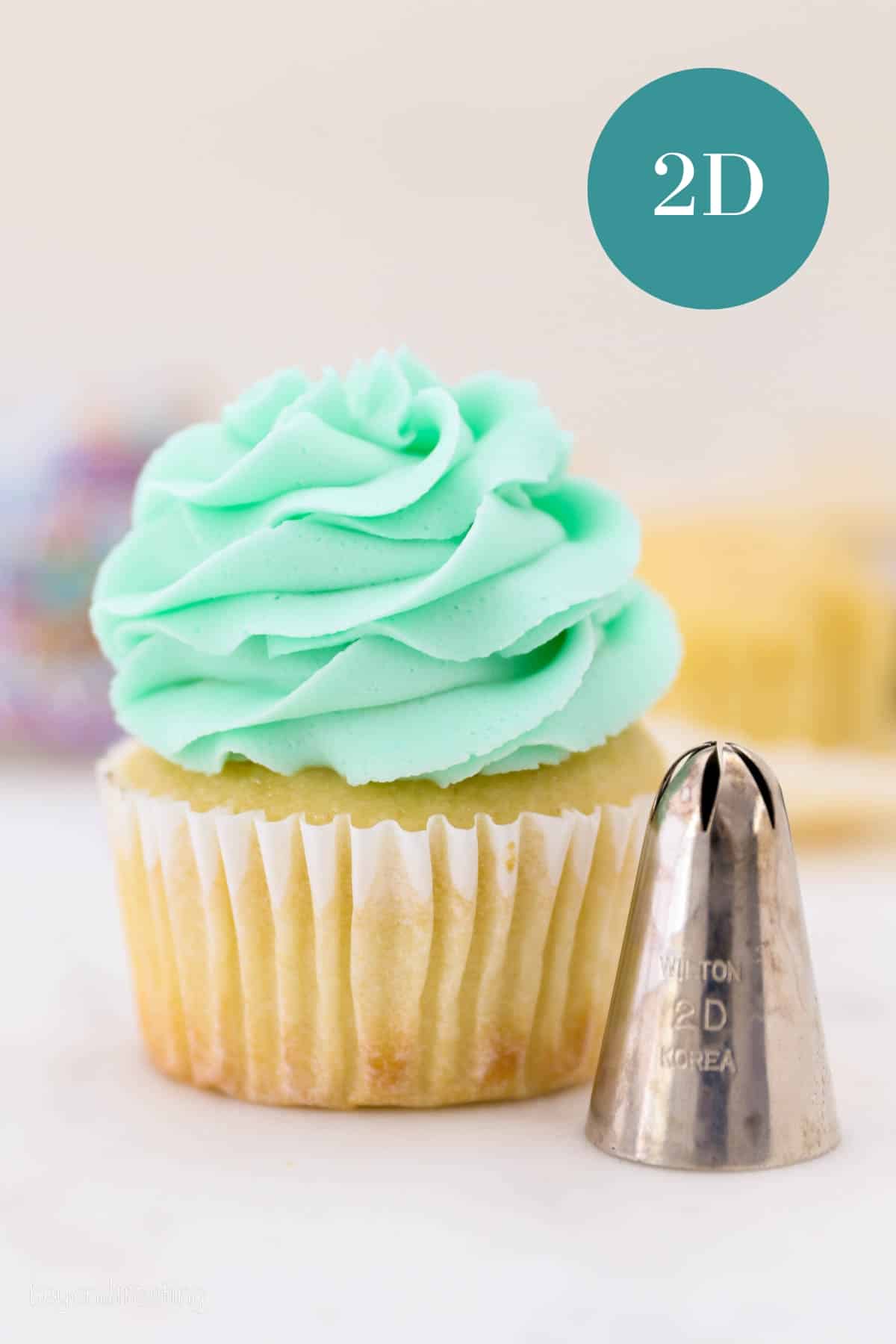 A 2D piping tip next to a frosted cupcake piped with a 2D swirl.