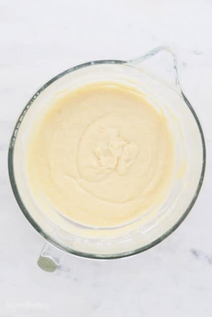 These lemon cupcakes are made with buttermilk and filled with bright citrus flavor, from the fluffy crumb to the creamy lemon frosting on top. Lemon cupcake batter in a glass mixing bowl with a spout.