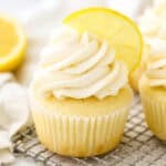 A frosted lemon cupcake topped with half of a lemon wedge.