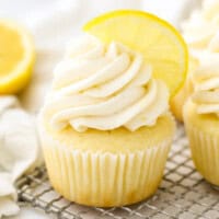 A frosted lemon cupcake topped with half of a lemon wedge.