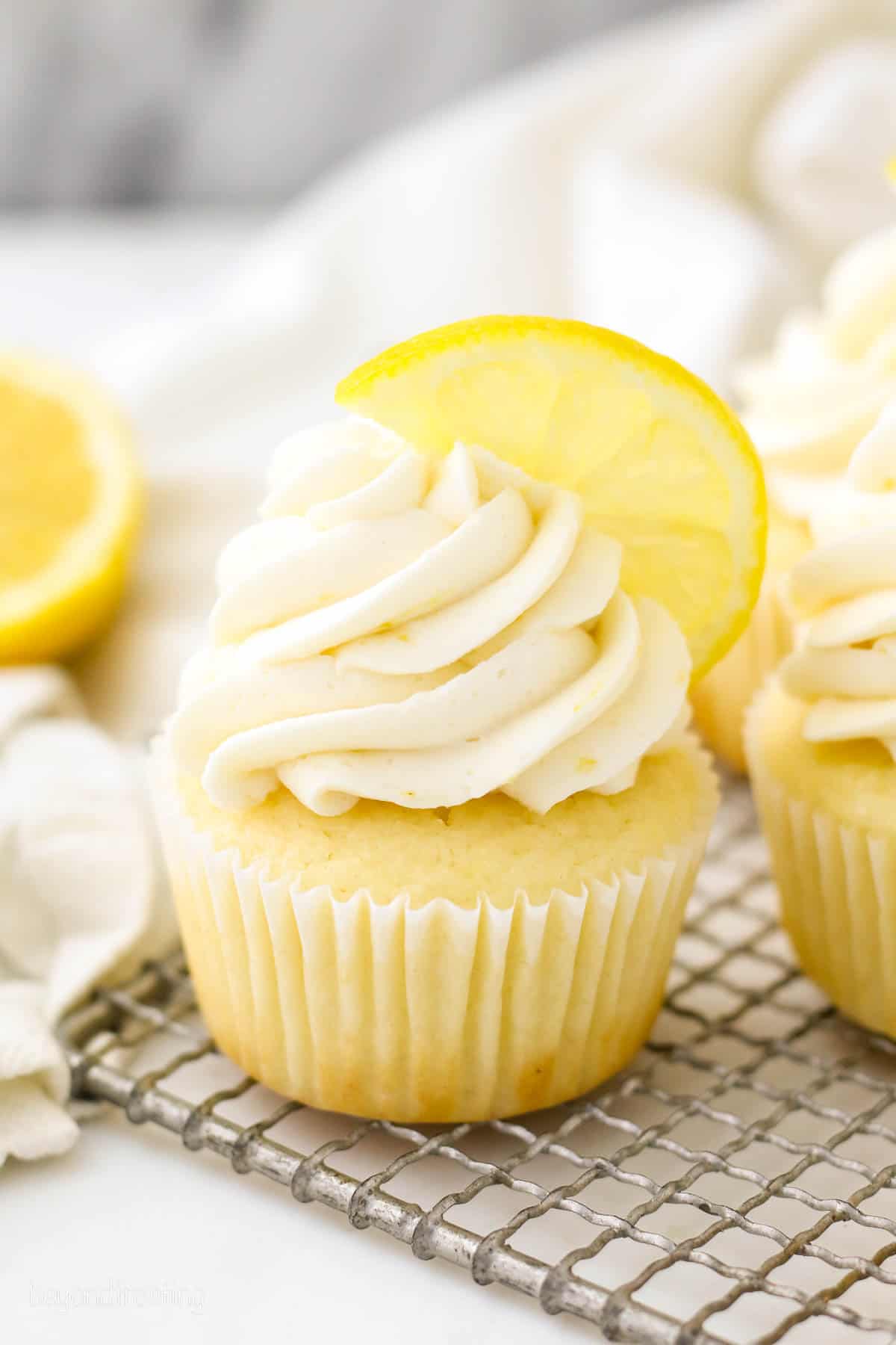 A frosted lemon cupcake topped with half of a lemon wedge.