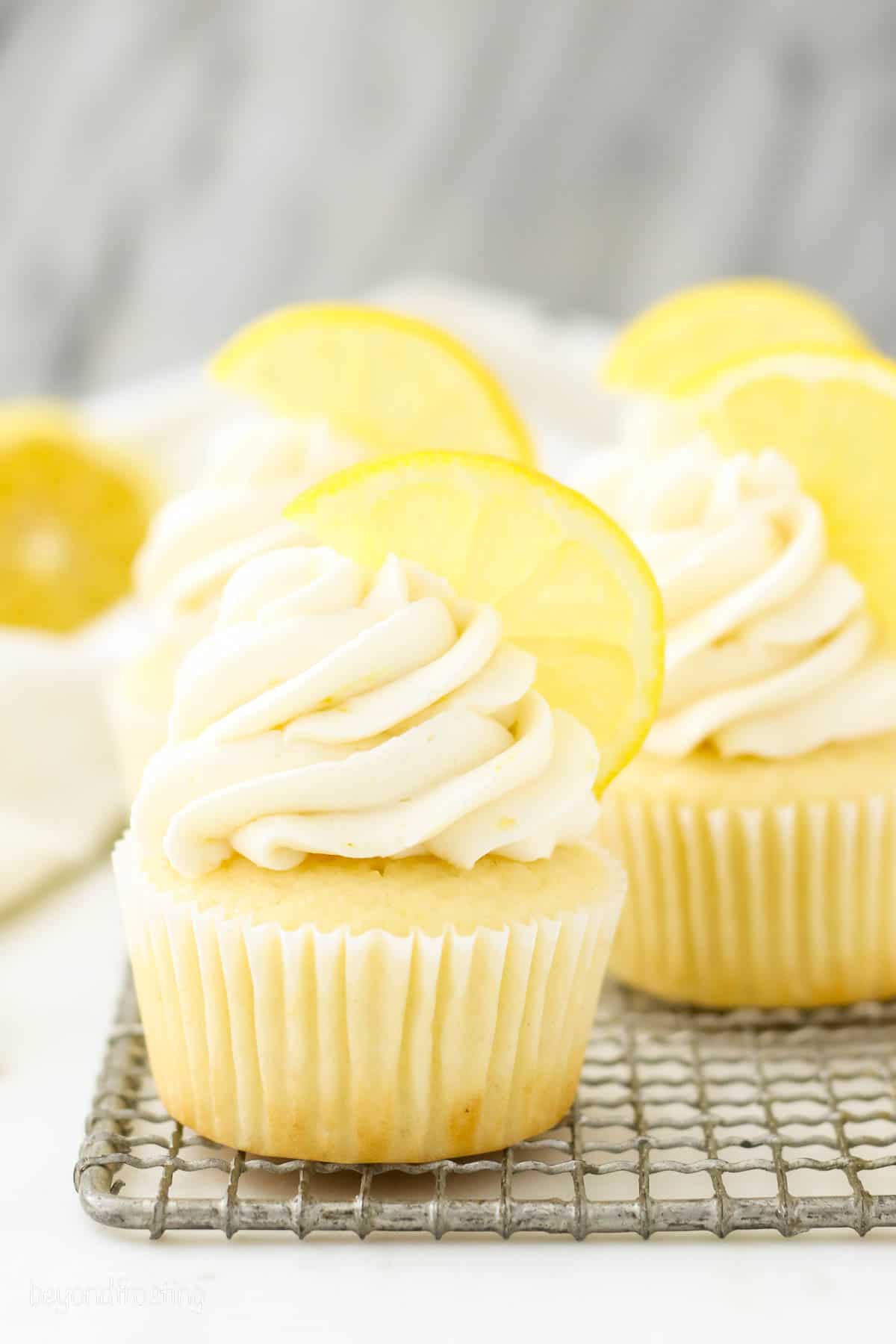 Frosted lemon cupcakes topped with lemon wedges.