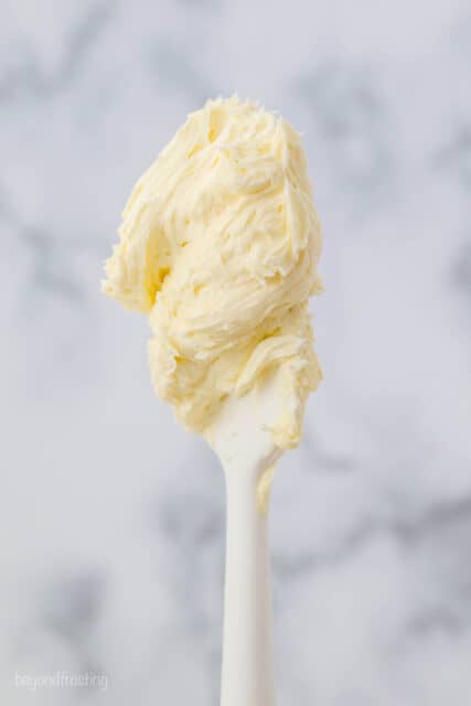 A white spatula with vanilla buttercream on it.