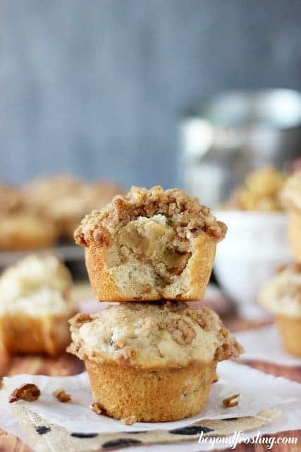 An apple pie muffin with a bite taken out of it stacked on top of another muffin